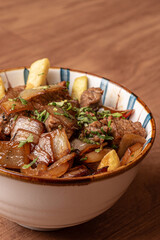 carne en salsa con cebolla, con papas fritas.