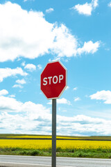 Stop sign against a background of a yellow field and blue sky