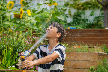 Teen cools off by playfully douse with stream of water from hose