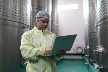 Winemaker inspecting quality the process of fermentation during manufacturing in winery factory and...
