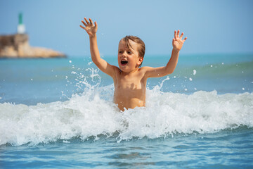 Carefree boy enjoys playful moment, embracing splash of sea foam