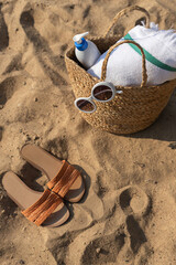 Jute beach bag and flip flops on the sand. Summer vacation lifestyle concept. Copy space	
