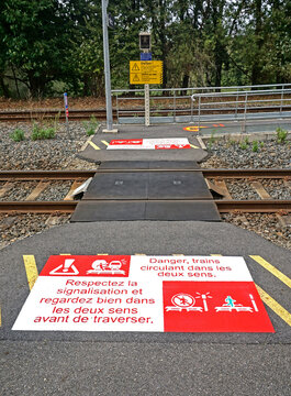 Rail travel and safety are critically important in Europe. Pedestrian railroad track crossing at a rural train station in France. French signs warn to obey signals, look both ways.
