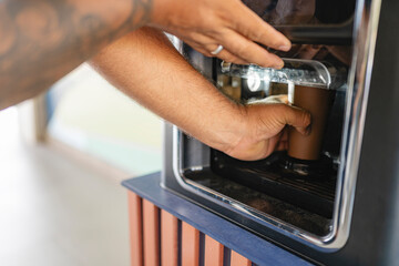 Anonymous man grabbing a cup of coffee from a coffee machine