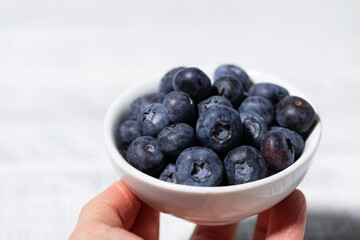 fresh blueberries in a white bowl in hand