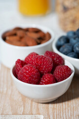 fresh berries, nuts, muesli and orange juice, vertical closeup