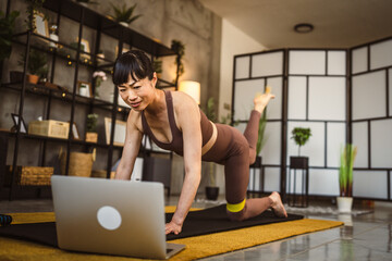 Mature japanese woman exercise at home watch the training on the laptop