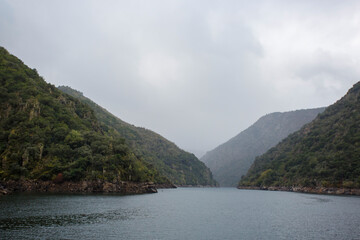 A river with a green hillside in the background in the Ribeira Sacra in Lugo, Galicia, Spain.