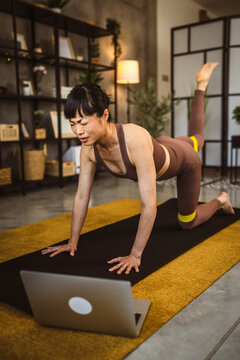 Mature japanese woman exercise at home watch the training on the laptop