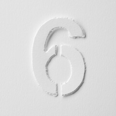 The number six is made of white paper on a white background.