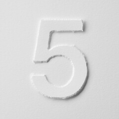 The number five is made of white paper on a white background.