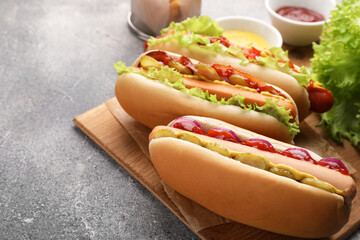Delicious hot dogs with different toppings served on grey table. Space for text