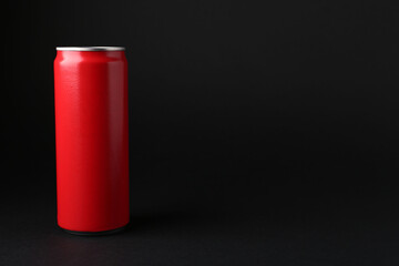 Energy drink in red can on black background, space for text