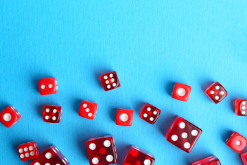 Many red game dices on light blue background, flat lay. Space for text