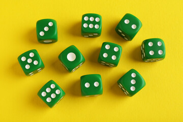 Many green game dices on yellow background, flat lay