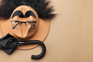 Man's face made of artificial hair, eyebrows, glasses and hat on beige background, top view. Space...