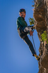 Caucasian man with black hair. Practicing rock climbing. He is happy because he has achieved his...