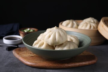 Delicious bao buns (baozi) in bowl on grey table, closeup