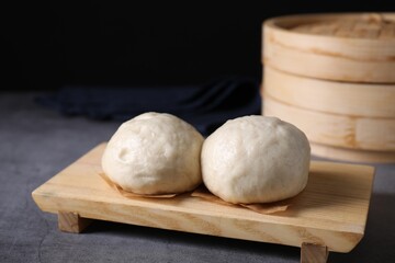 Delicious Chinese steamed buns on grey textured table, closeup