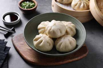 Delicious bao buns (baozi) in bowl on grey table, closeup
