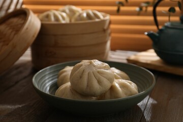 Delicious bao buns (baozi) in bowl on wooden table, closeup