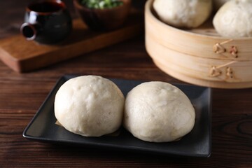 Fototapeta na wymiar Delicious Chinese steamed buns on wooden table, closeup