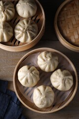 Fototapeta premium Delicious bao buns (baozi) on wooden table, flat lay