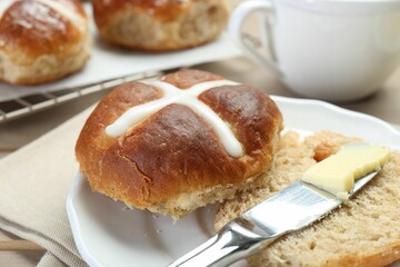 Tasty hot cross bun and knife with butter on table, closeup
