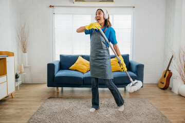 House cleaning turns into a joyous affair Asian housewife sings happily using a vacuum cleaner as a...