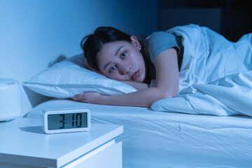 Annoyed, stressed, anxiety asian young woman suffering from insomnia, frustrated awake on bed at night, headache or migraine, health care problem, disturbed trouble of loud noise, unable sleepless.