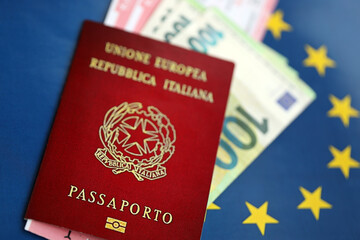 Italian passport of European Union and airlines tickets on blue flag background close up. Tourism and travel concept