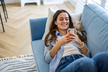 Smiling woman using mobile phone on sofa in living room at home
