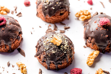 Round chocolate cakes. Decorated with candied raspberries. Light background.