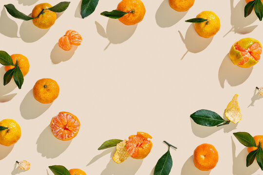 Fresh tangerines on beige background with sunlight shadows, minimal aesthetic citrus fruits as summer food frame, organic orange colored mandarin with green leaves top view, copy space