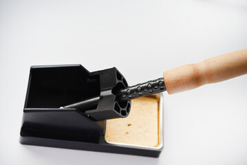 Soldering iron with a wooden handle in the holder. A soldering iron stand.