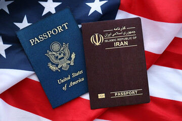 Passport of Iran Republic with US Passport on United States of America folded flag close up