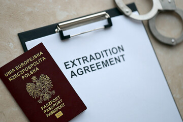 Passport of Poland and Extradition Agreement with handcuffs on table close up