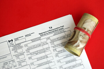 Canadian T4 tax form Statement of remuneration paid lies on table with canadian money bills close...