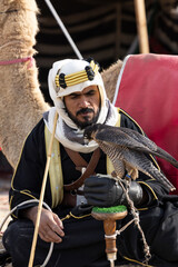 Saudi man in traditional clothing with his falcon in a desert