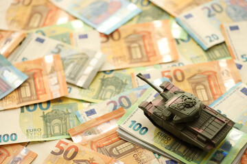 Many euro banknotes and tank. Lot of bills of European union currency and green tank close up