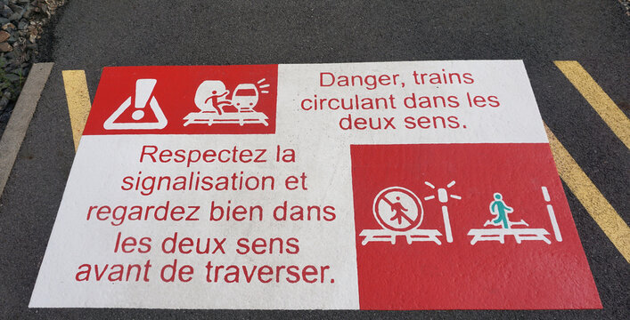 Railroad travel is common in Europe, even in rural areas. Railroad level crossing sign painted on a sidewalk in France warns pedestrians to obey signals and look both ways.