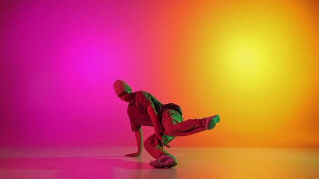 Dynamic video of contemporary dancer in motion in neon light against gradient pink-yellow background. Concept of art, hobby, sport, creativity, fashion and style, action. Ad