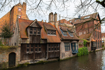 Fototapeta na wymiar Classic view of channels of Bruges (Brugge), Belgium. Medieval fairytale city. Venice of the North, cityscape of Flanders. Medieval ancient houses made of old bricks at water channel in old town.