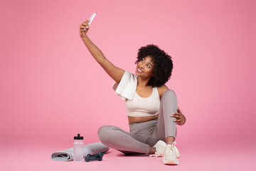 Lady taking selfie with smartphone on pink background