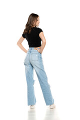 Young female model wearing ripped jeans and black shirt posing on a white background. Back, rear view