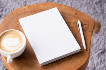 blank book mockup on coffee table with cappuccino, pen and grey rug