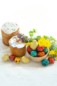 Easter cakes (Paska, Kulich), chickens toys and colorful eggs with flowers on white wooden table. Easter holiday background. Festive composition for spring season.