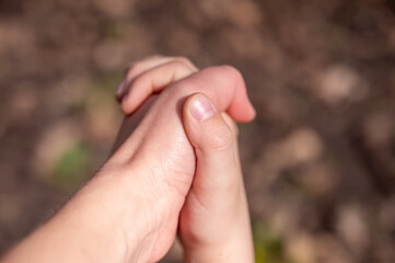 Mother and baby holding hands in the park. Close up