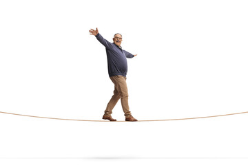 Full length shot of a mature man walking on a rope isolated on white background