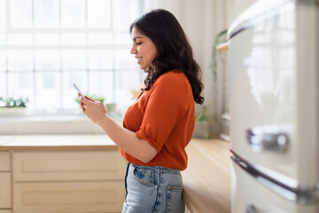 Woman using smartphone in a sunny kitchen